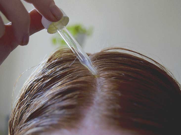 Woman applying hair oil using dropper